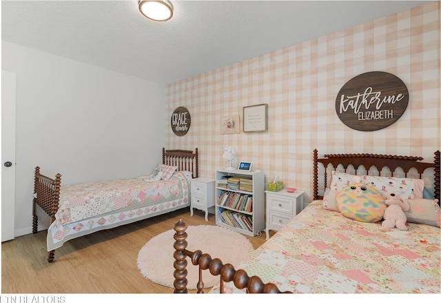 bedroom featuring wallpapered walls and wood finished floors