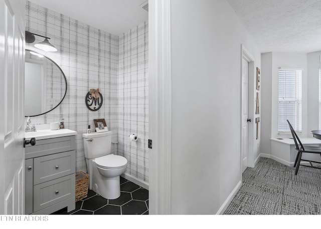 bathroom featuring vanity, toilet, tile patterned floors, a textured ceiling, and baseboards