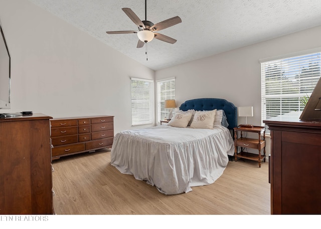 bedroom featuring light wood-style floors, a textured ceiling, lofted ceiling, and multiple windows