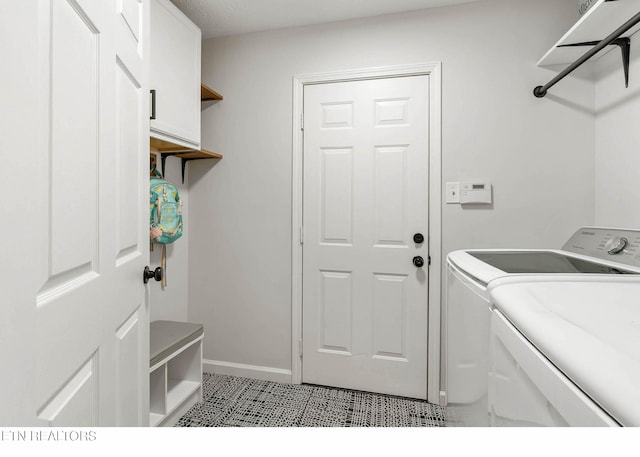 laundry area with baseboards, light tile patterned flooring, cabinet space, and washer and dryer