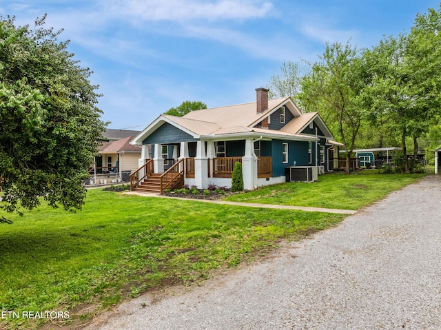 bungalow-style home featuring a front lawn, a chimney, metal roof, a porch, and driveway