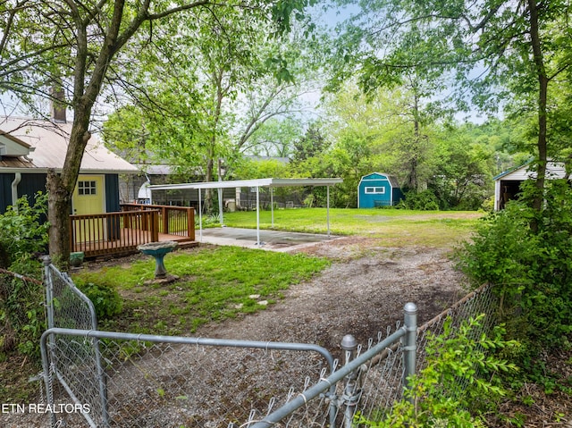 view of yard with a storage shed, fence private yard, an outbuilding, a detached carport, and driveway