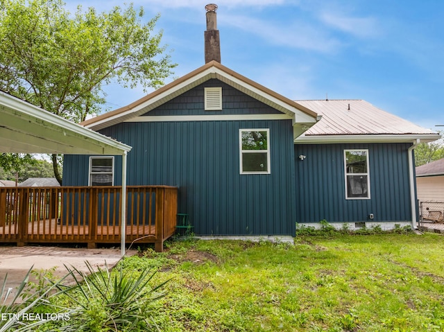 rear view of property with crawl space, a yard, a deck, and metal roof