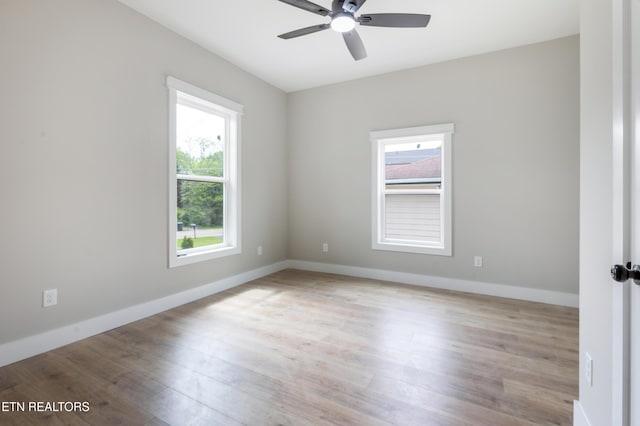 unfurnished room with a ceiling fan, baseboards, a healthy amount of sunlight, and wood finished floors