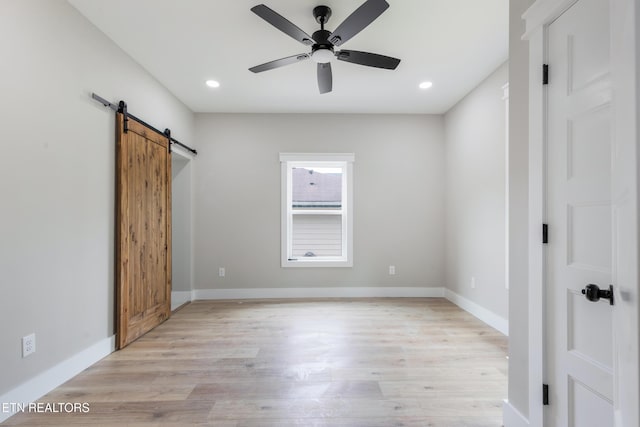 unfurnished bedroom featuring baseboards, light wood-style flooring, recessed lighting, and a barn door