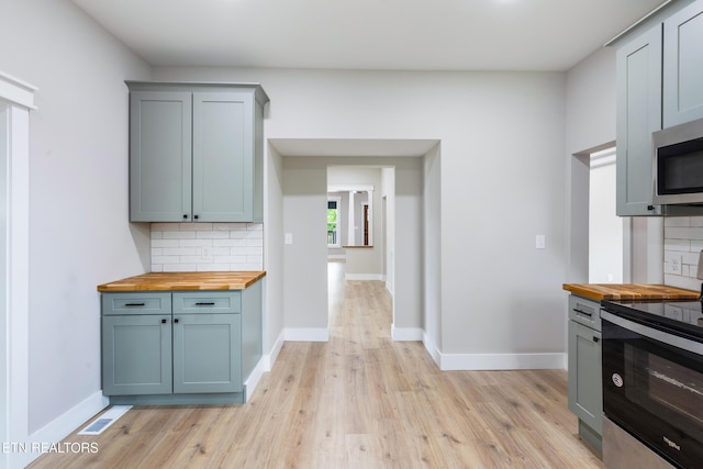 kitchen featuring backsplash, stainless steel appliances, and wood counters