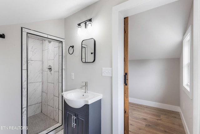 full bathroom featuring vanity, baseboards, wood finished floors, and tiled shower