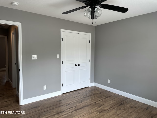 unfurnished bedroom featuring a ceiling fan, baseboards, wood finished floors, and a closet