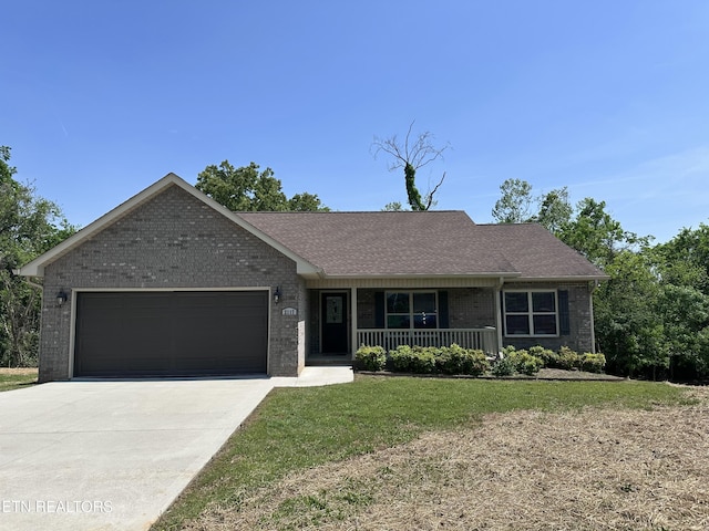 ranch-style home featuring an attached garage, a front lawn, brick siding, covered porch, and driveway