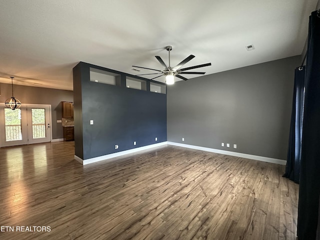 spare room featuring baseboards, visible vents, dark wood-style floors, and ceiling fan with notable chandelier