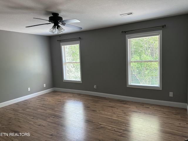 empty room with baseboards, a textured ceiling, visible vents, and wood finished floors