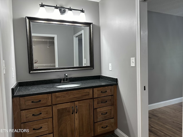 bathroom featuring vanity, baseboards, and wood finished floors