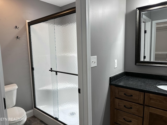 bathroom featuring vanity, tile patterned flooring, toilet, and a shower stall