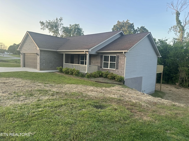view of front of property featuring a front lawn, an attached garage, brick siding, a porch, and driveway