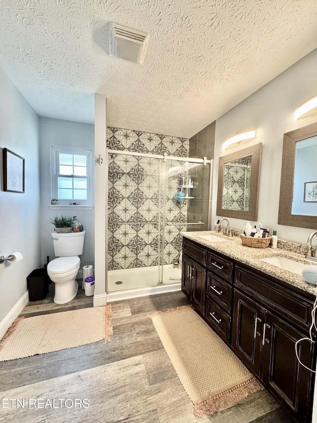 bathroom with double vanity, visible vents, a shower stall, and a sink