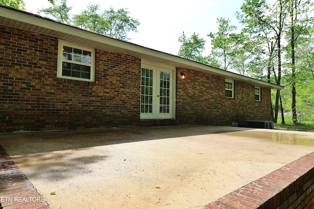 back of house with a patio, brick siding, french doors, and central AC