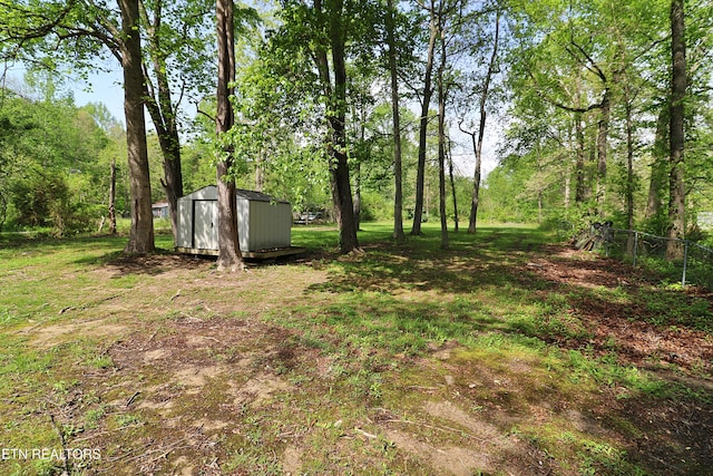 view of yard featuring an outbuilding, a shed, and fence