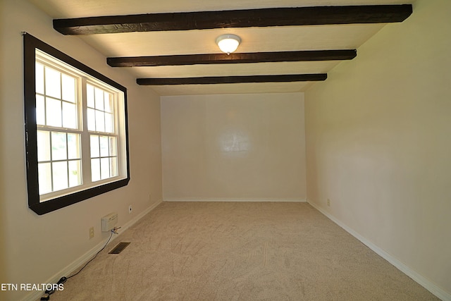 spare room featuring baseboards, beamed ceiling, carpet flooring, and visible vents