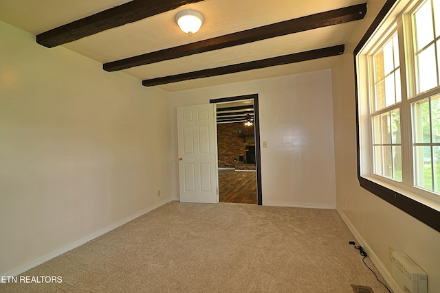 carpeted empty room with baseboards and beam ceiling