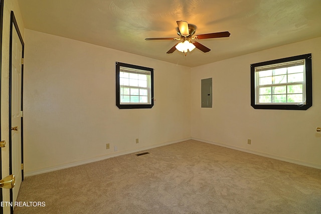 carpeted spare room with electric panel, baseboards, a ceiling fan, and visible vents