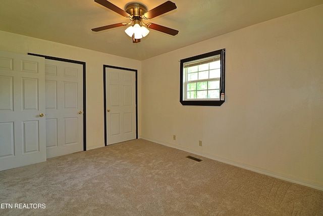 unfurnished bedroom with baseboards, carpet flooring, visible vents, and a ceiling fan