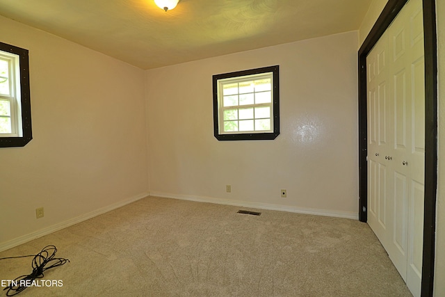 unfurnished bedroom featuring carpet flooring, baseboards, and multiple windows
