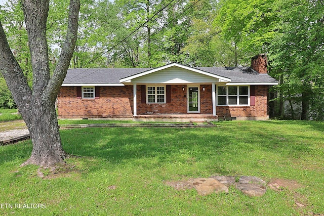single story home featuring a chimney, a shingled roof, brick siding, and a front lawn