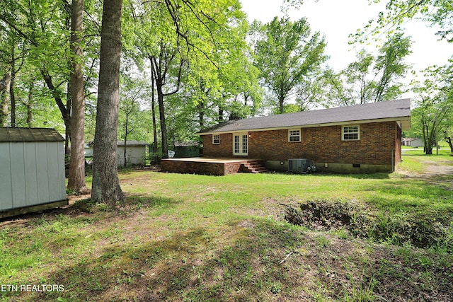 rear view of house with a yard, an outbuilding, french doors, and a storage unit