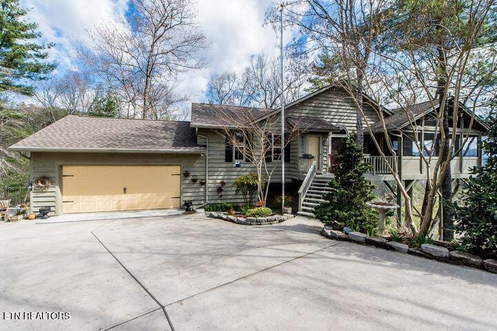ranch-style house featuring stairway, an attached garage, and driveway
