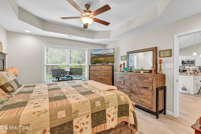 bedroom with a ceiling fan, visible vents, a tray ceiling, recessed lighting, and light wood-style flooring