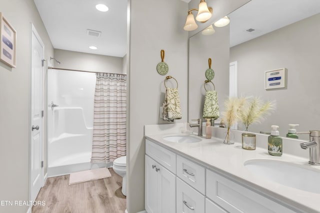 full bathroom with toilet, curtained shower, a sink, and wood finished floors