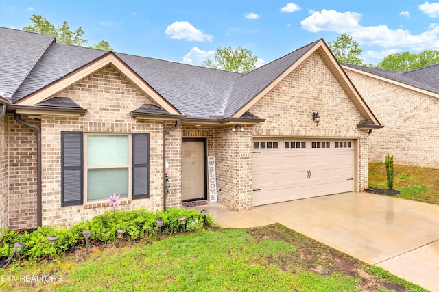 view of front of house with brick siding, driveway, roof with shingles, and a garage