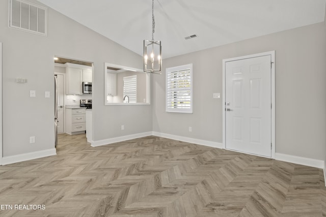 unfurnished dining area featuring baseboards, visible vents, an inviting chandelier, and lofted ceiling