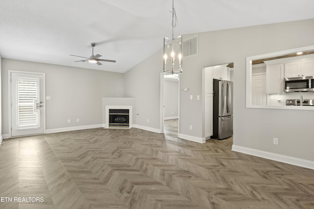 unfurnished living room featuring visible vents, a fireplace, baseboards, high vaulted ceiling, and ceiling fan with notable chandelier
