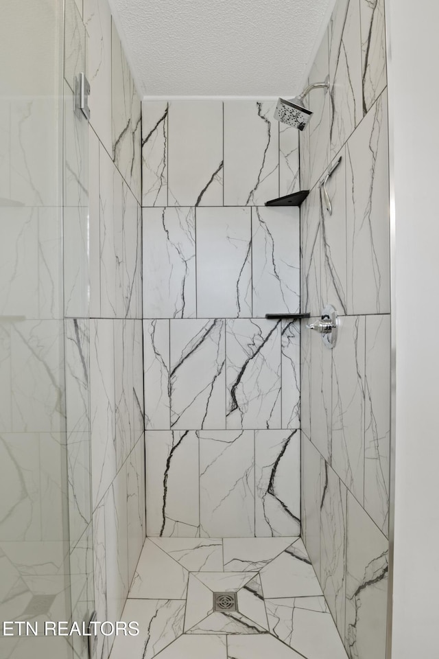 bathroom with a tile shower and a textured ceiling