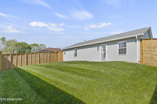 rear view of house featuring a lawn and a fenced backyard