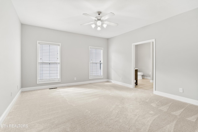 empty room featuring ceiling fan, light carpet, and baseboards