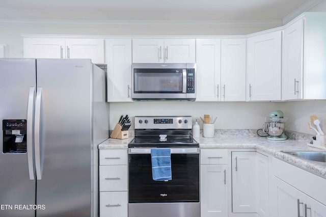kitchen with a sink, appliances with stainless steel finishes, white cabinets, and ornamental molding