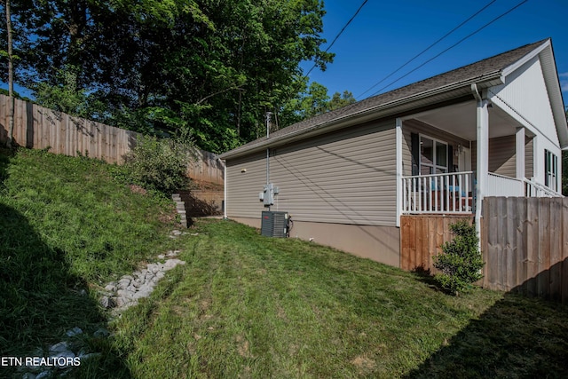 view of side of property featuring a porch, fence, and a yard