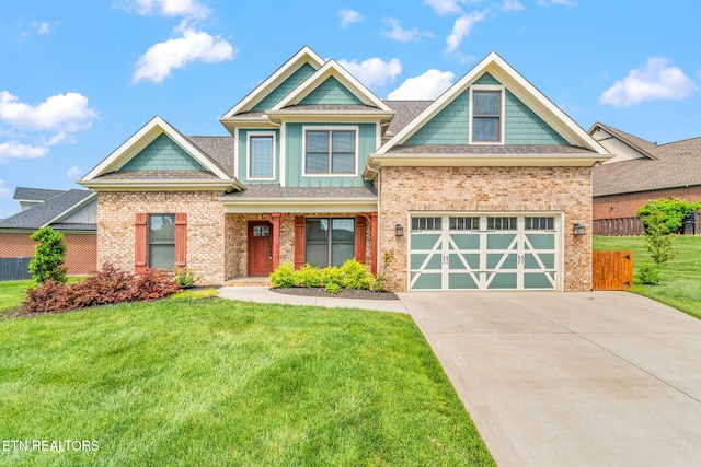 craftsman-style home with a garage, fence, a front yard, brick siding, and concrete driveway