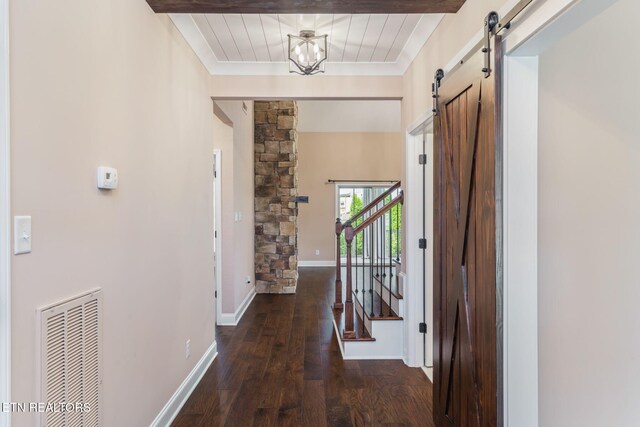 hallway featuring a barn door, ornamental molding, hardwood / wood-style floors, and visible vents