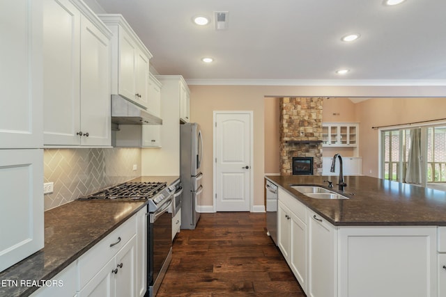 kitchen with a sink, stainless steel appliances, white cabinetry, tasteful backsplash, and under cabinet range hood