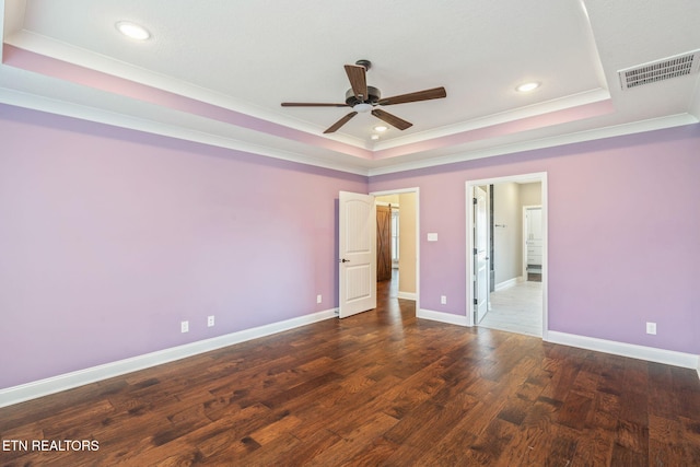 unfurnished bedroom featuring baseboards, wood finished floors, a tray ceiling, visible vents, and ornamental molding