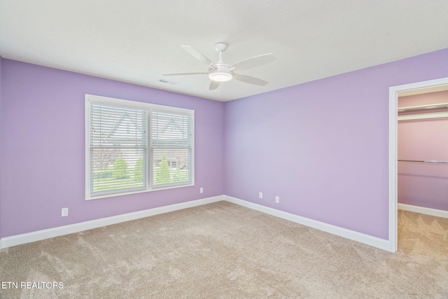 unfurnished bedroom with visible vents, light carpet, baseboards, a walk in closet, and ceiling fan