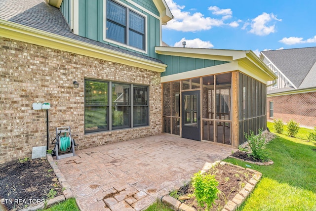 rear view of property featuring a sunroom, brick siding, board and batten siding, a patio area, and a lawn