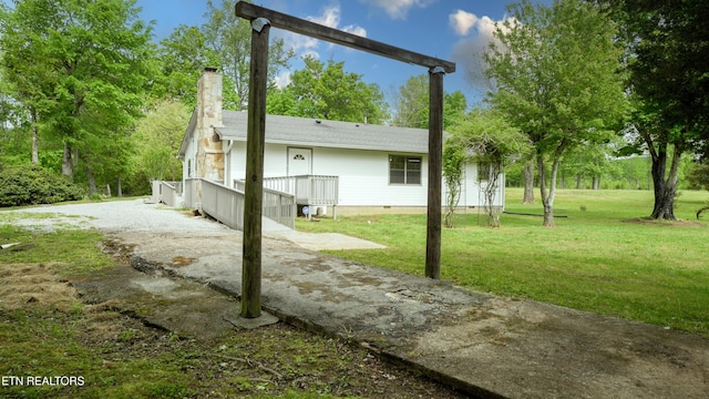 exterior space with crawl space, driveway, a chimney, a lawn, and a deck
