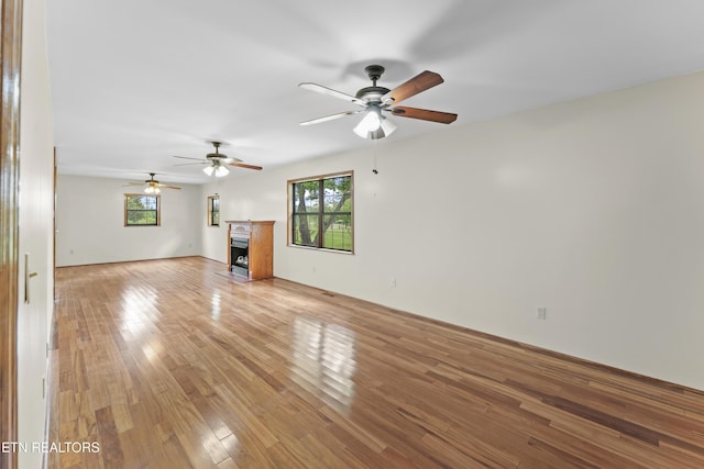 unfurnished living room with a ceiling fan, light wood-style flooring, and a fireplace