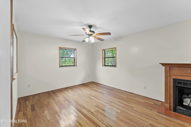 unfurnished living room featuring a healthy amount of sunlight, a ceiling fan, and light wood-type flooring
