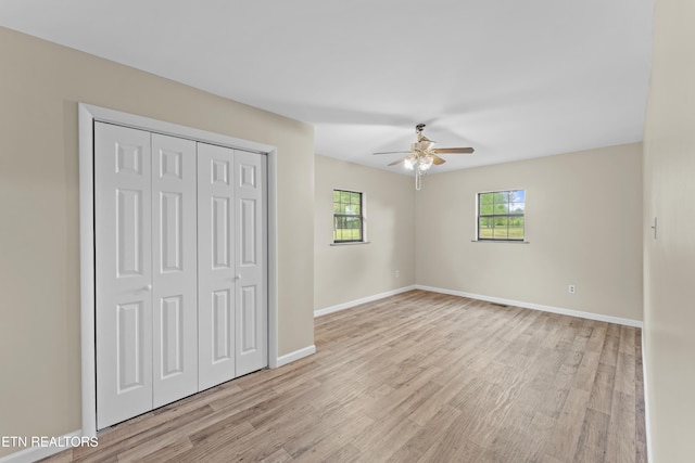 unfurnished bedroom featuring light wood finished floors, a closet, and baseboards