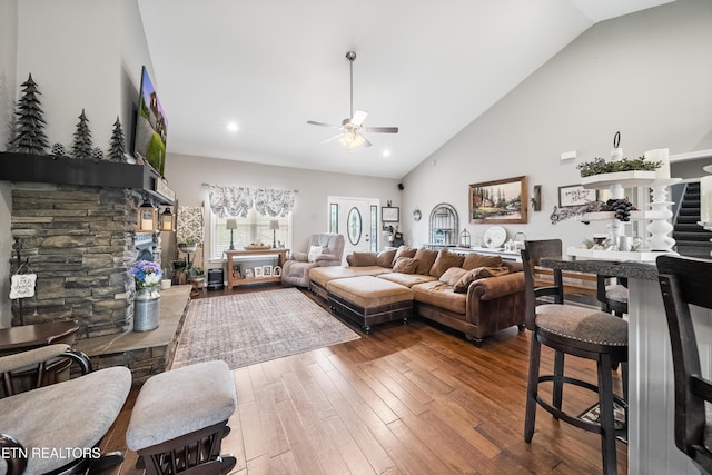 living area featuring ceiling fan, a fireplace, high vaulted ceiling, wood-type flooring, and recessed lighting